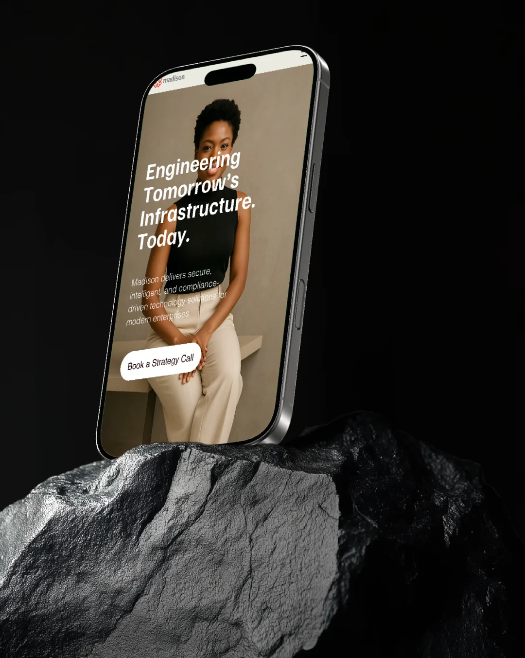 Madison mobile homepage on a phone resting on dark rock: headline Engineering Tomorrow's Infrastructure Today with a Book a Strategy Call button